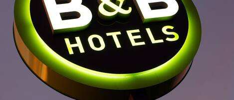 A circular sign with the text "B&B HOTELS" against a twilight sky.