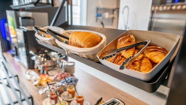 A buffet with croissants and pastries, a toaster, and various condiments.
