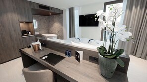 A modern bathroom with a large bathtub, a vanity with a sink, a mirror, and a potted orchid. - Radisson Blu Hotel Bruges (Bruges)