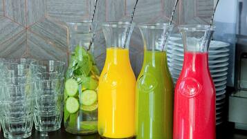 Variedad de bebidas coloridas en botellas de vidrio y vasos, con un backsplash de azulejos al fondo.