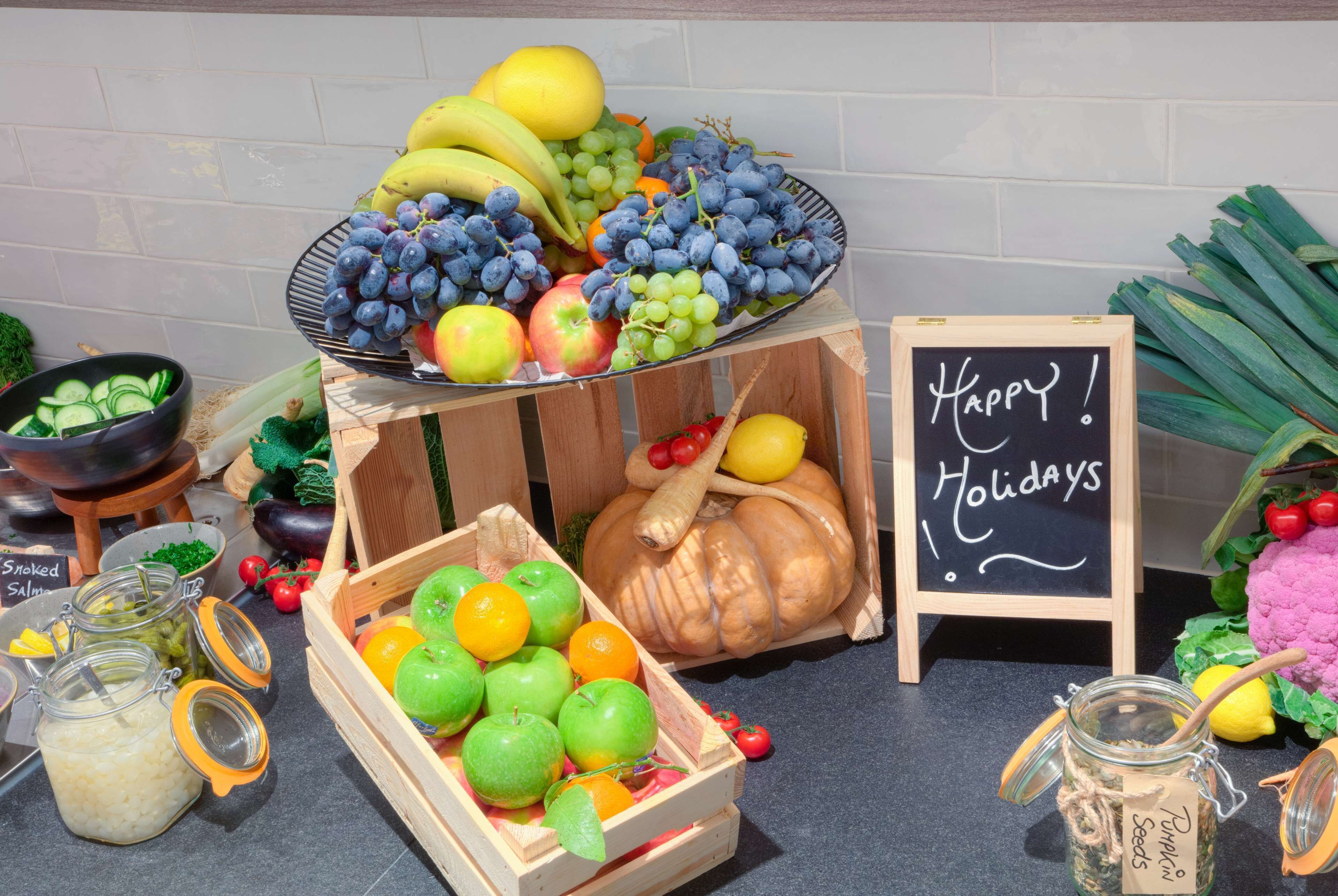 Een presentatie van fruit en groenten met een bordje 'Happy Holidays'.