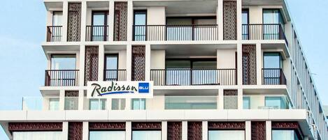 A multi-story hotel with balconies, a sign reading "Radisson BLU," and a modern architectural design.