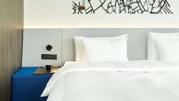 Una habitación de hotel con cama, mesita de noche, lámpara de pared y un adorno en la pared.