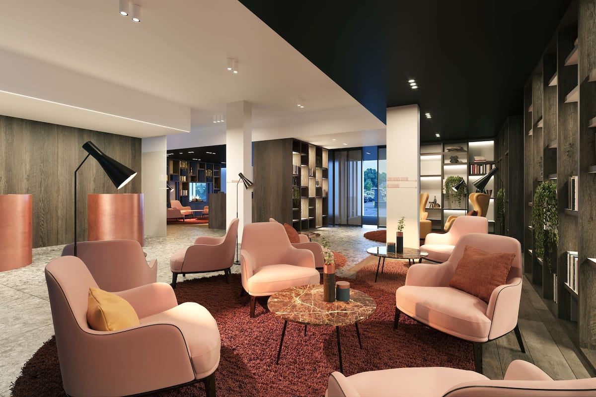 A modern lobby with seating areas, a coffee table, and bookshelves.
