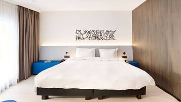 Ein modernes Hotelzimmer mit einem großen Bett, einer blauen Akzentwand und einem dekorativen Kunstwerk darüber.