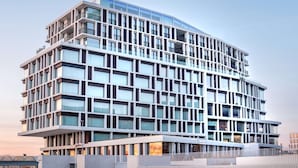 A modern multi-story hotel with a curved facade, large windows, and balconies. - Radisson Blu Hotel Bruges (Bruges)