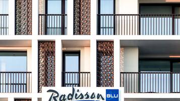 La façade d’un hôtel, ornée de balcons et de murs aux motifs géométriques, et sur laquelle on peut lire l’inscription « Radisson Blu ».