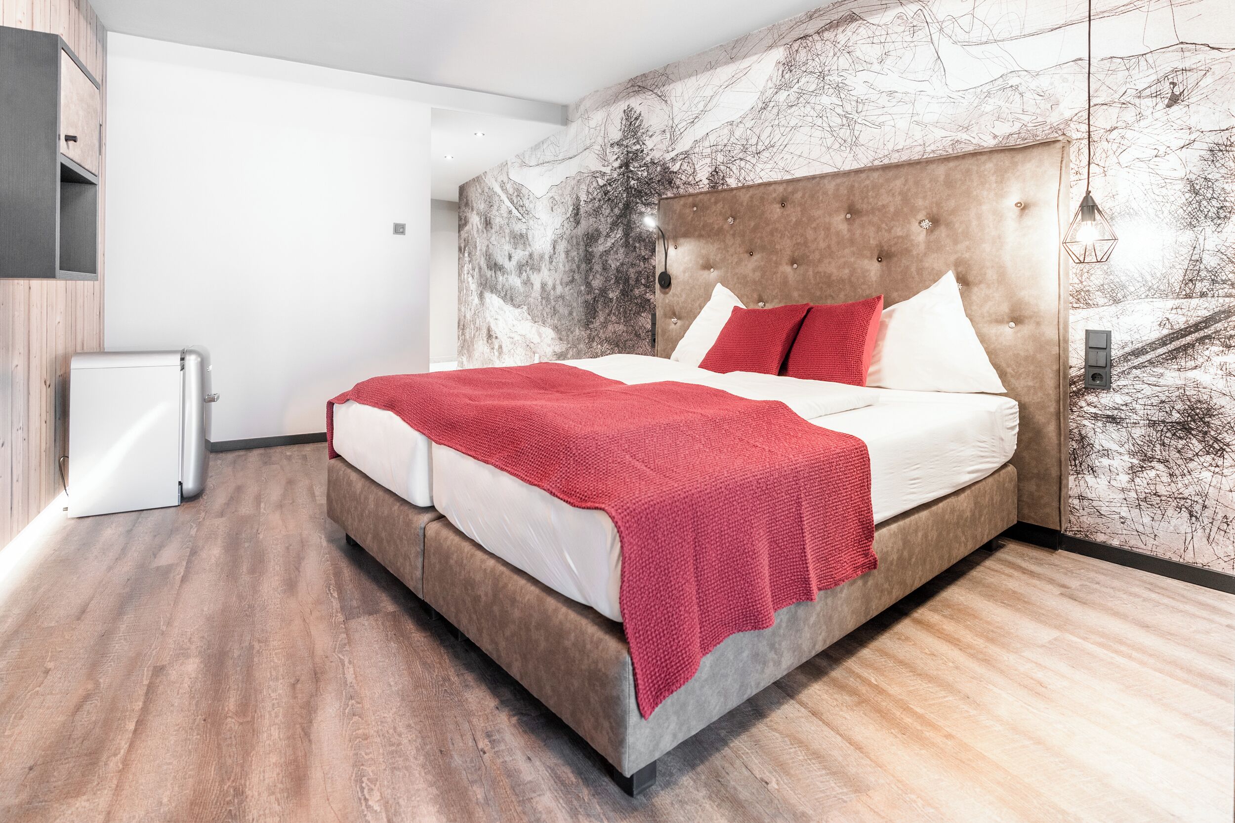 A modern bedroom with a large bed, a marble-patterned wall, and a wooden floor.