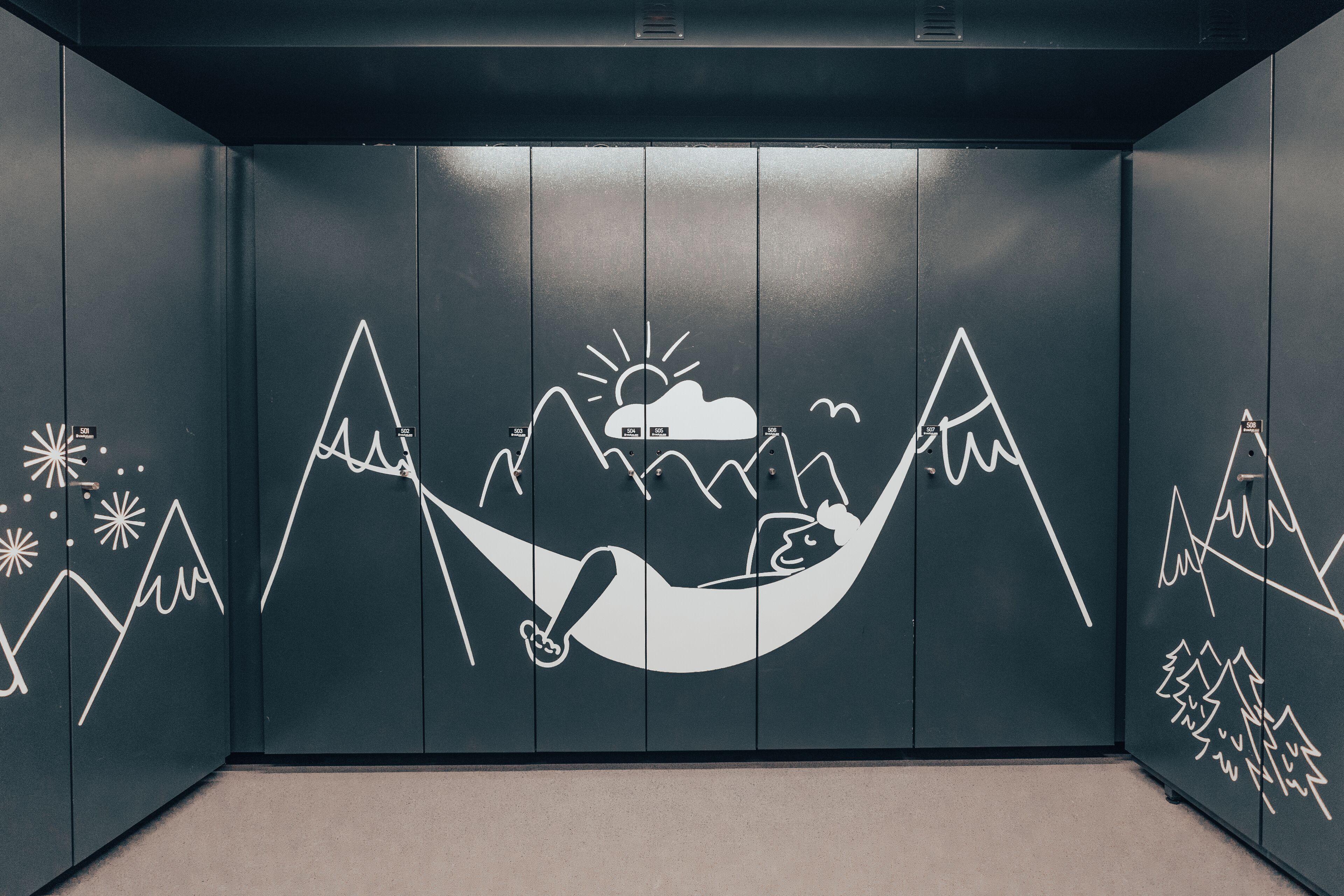 A room with a hammock and mountain-themed wall art.