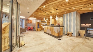 Een modern interieur met houten plafondpanelen, een receptiebalie en een zithoek met stoelen en tafels.