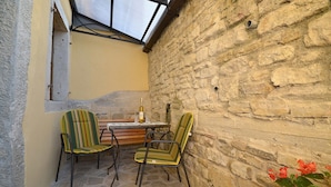 A small outdoor seating area with two striped chairs and a table, a bottle, and a glass on the table. - Bella Vista Apartments (Motovun)