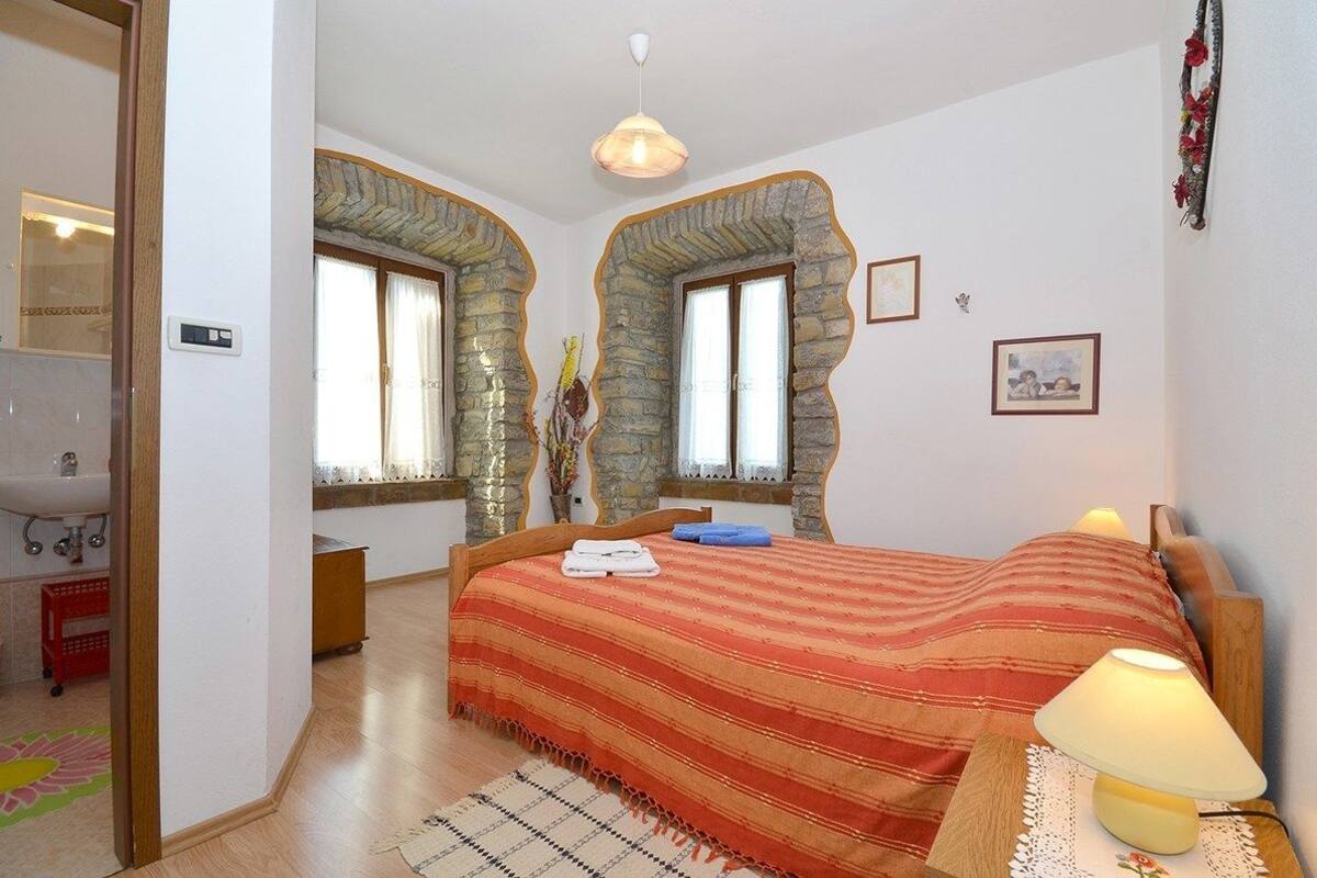 A bedroom with a bed, a nightstand, a lamp, and a window with curtains.