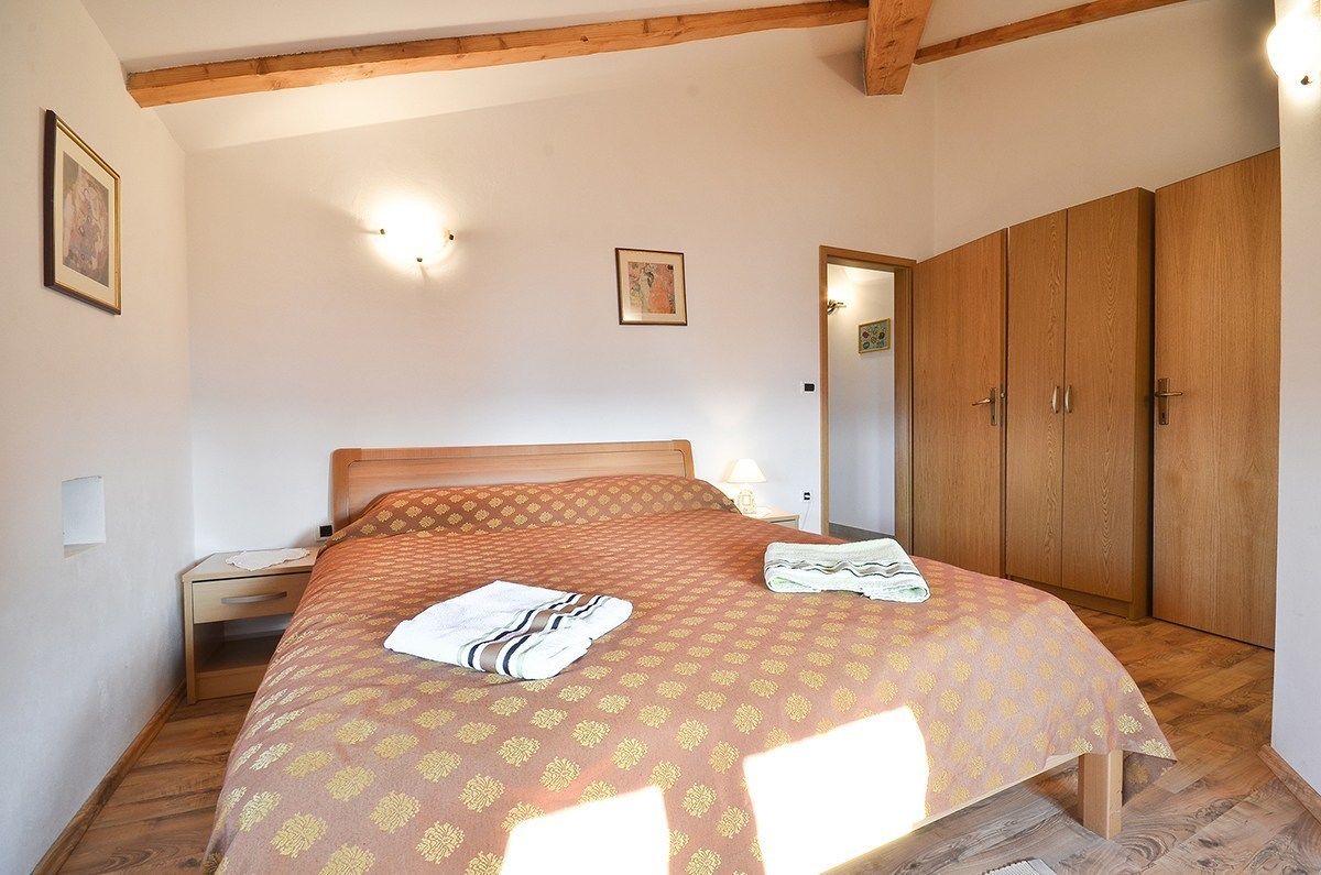 Een slaapkamer met een bed, een houten garderobe en een nachtkastje.