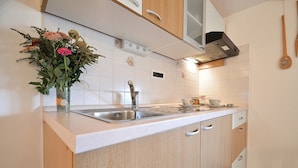 A kitchen with a double sink, wooden cabinets, and a decorative vase with flowers. - Bella Vista Apartments (Motovun)