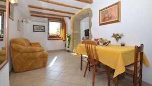 A dining area with a table set for two, a sofa, and a stone archway. - Bella Vista Apartments (Motovun)