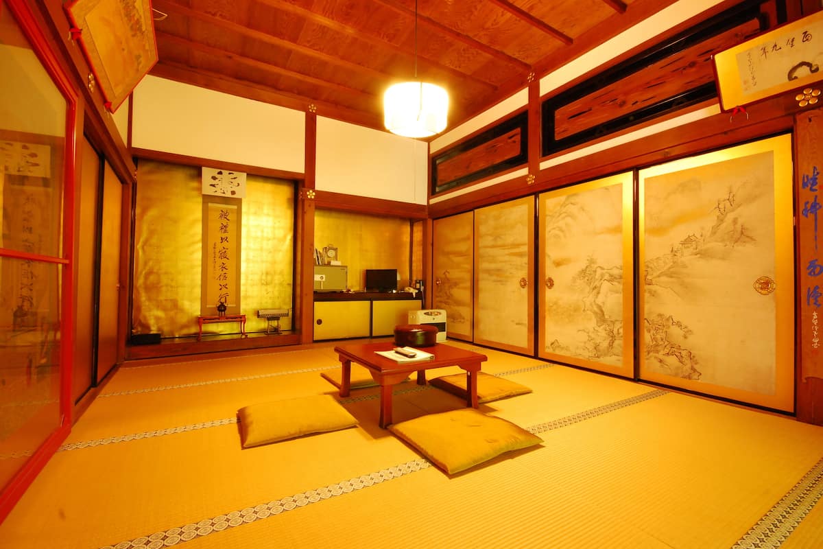 A traditional Japanese room with tatami flooring, a low wooden table, and sliding doors with calligraphy.
