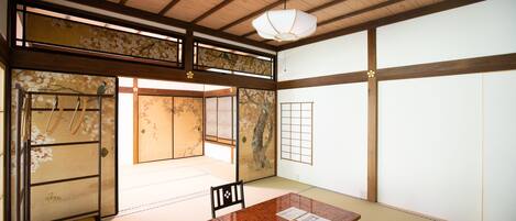 A traditional Japanese room with tatami flooring, a low wooden table, a chair, and a sliding door.