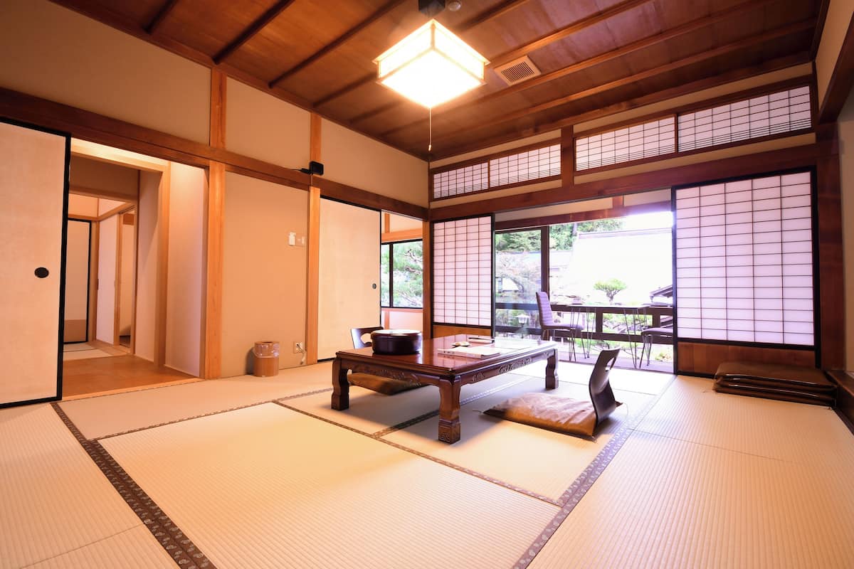 A traditional Japanese room with tatami flooring, a wooden table, and sliding doors.