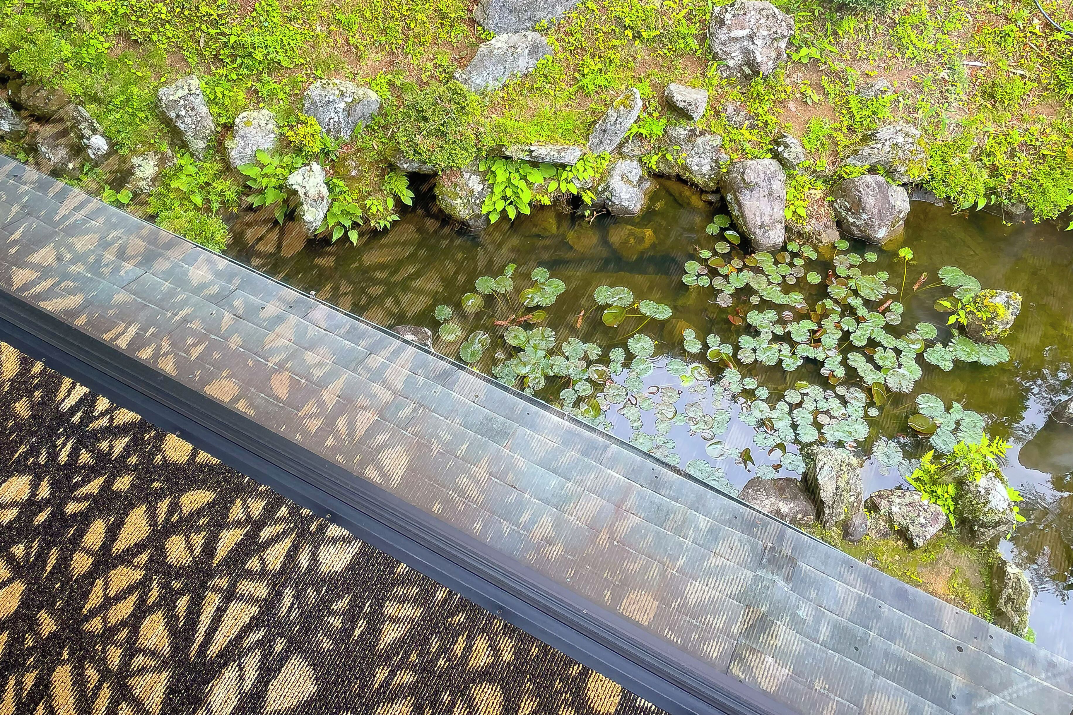 A bridge over a water body with rocks and greenery.
