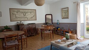 Uma sala de jantar com mobiliário de madeira, um mapa grande na parede e uma estante com livros e objetos decorativos.