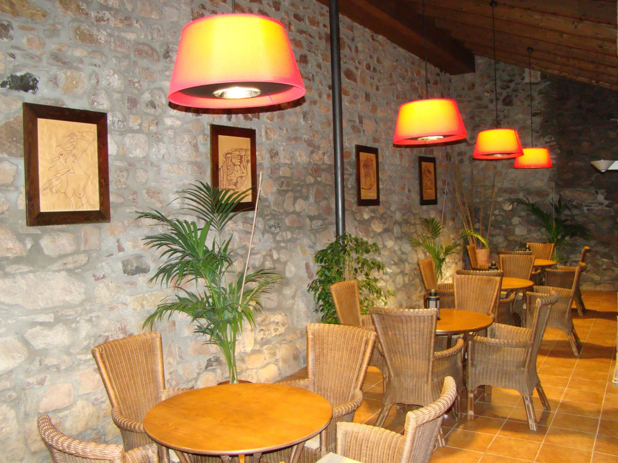 Un restaurante con mobiliario de mimbre, paredes de piedra y obras de arte enmarcadas.