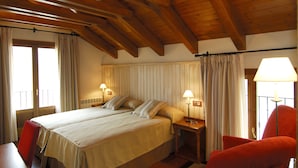 A hotel room with a large bed, two bedside tables, a red chair, and a balcony with curtains. - Diamo (Castejon de Sos)