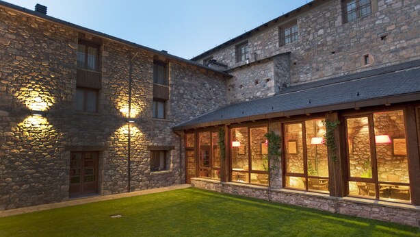 A stone building with a well-maintained lawn and large windows. - Diamo (Castejon de Sos)