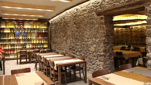 A restaurant with stone walls, wooden tables, and a wine display. - Diamo (Castejon de Sos)