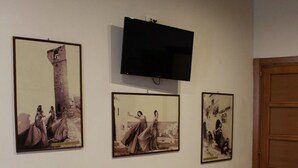 A living room with a white sofa, a flat-screen TV mounted on the wall, and three framed pictures depicting historical scenes. - Centro Storico B&B (Foggia)