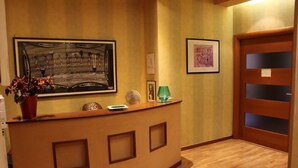 A reception desk with a framed abstract painting, a leopard print object, and a green glass. - Centro Storico B&B (Foggia)