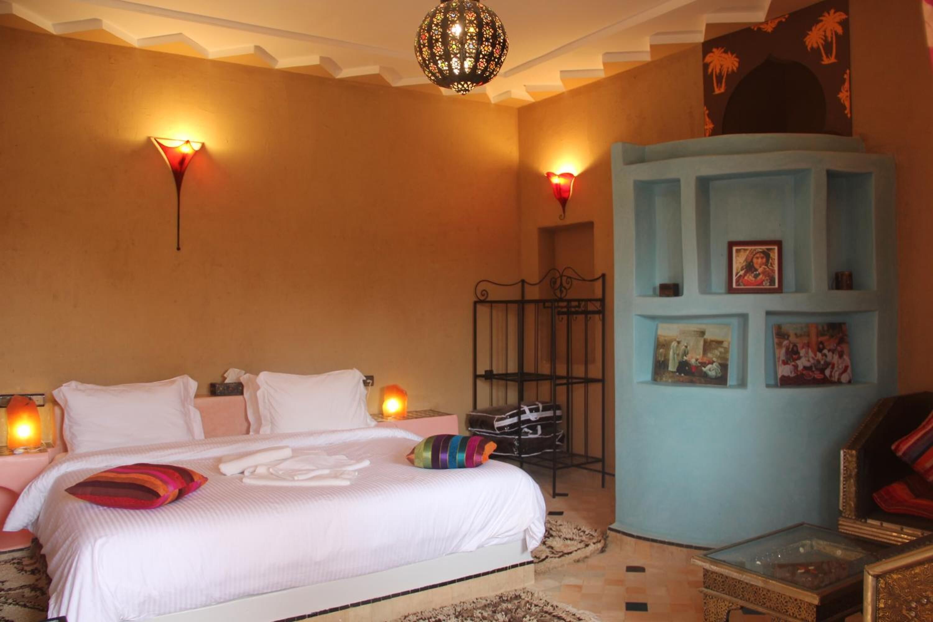 Une chambre à coucher comprenant un lit, des lampes de chevet, une armoire et un luminaire décoratif au plafond.