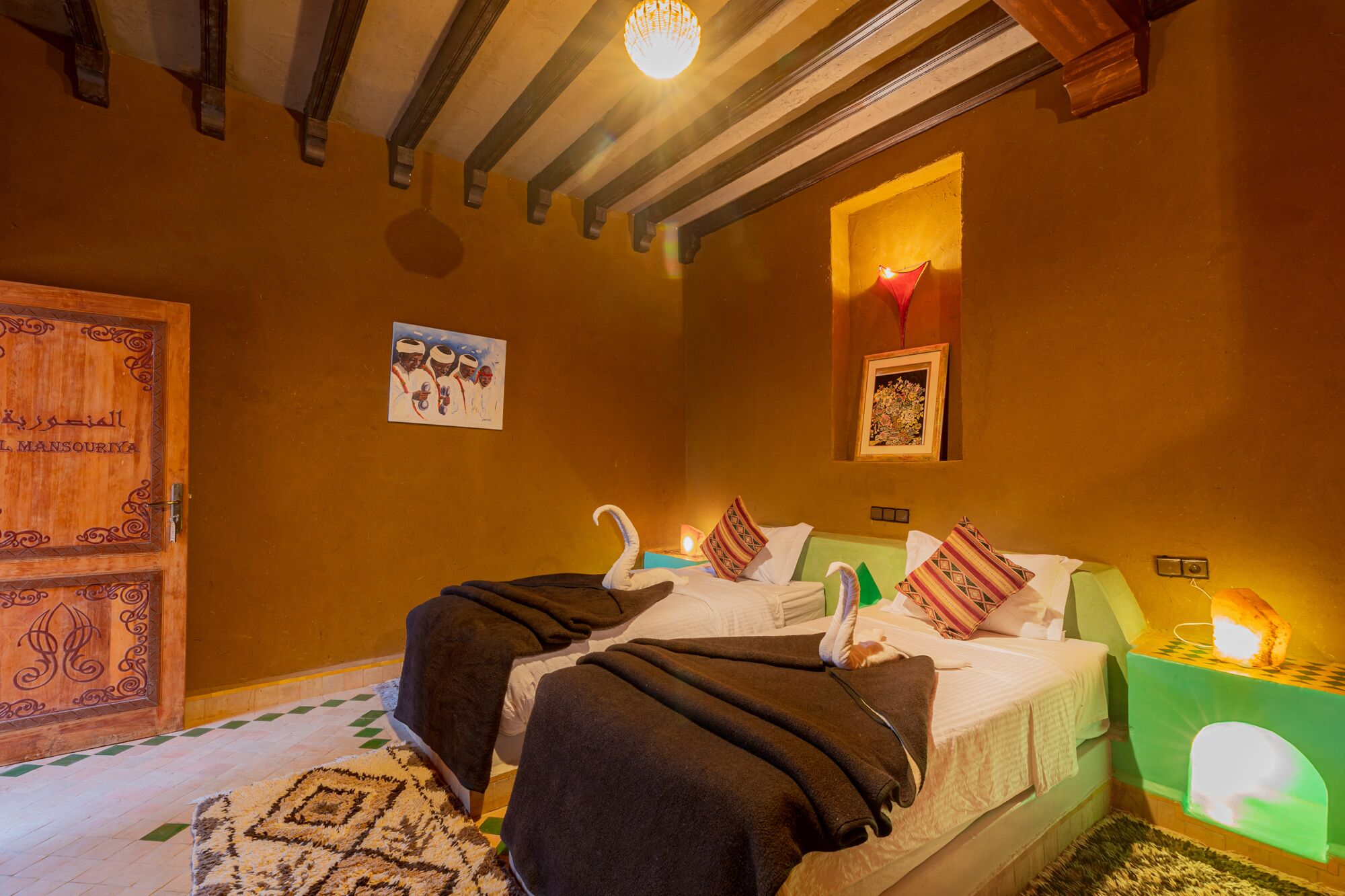 Una habitación acogedora con una cama, una puerta de madera y un cuadro colgado en la pared.