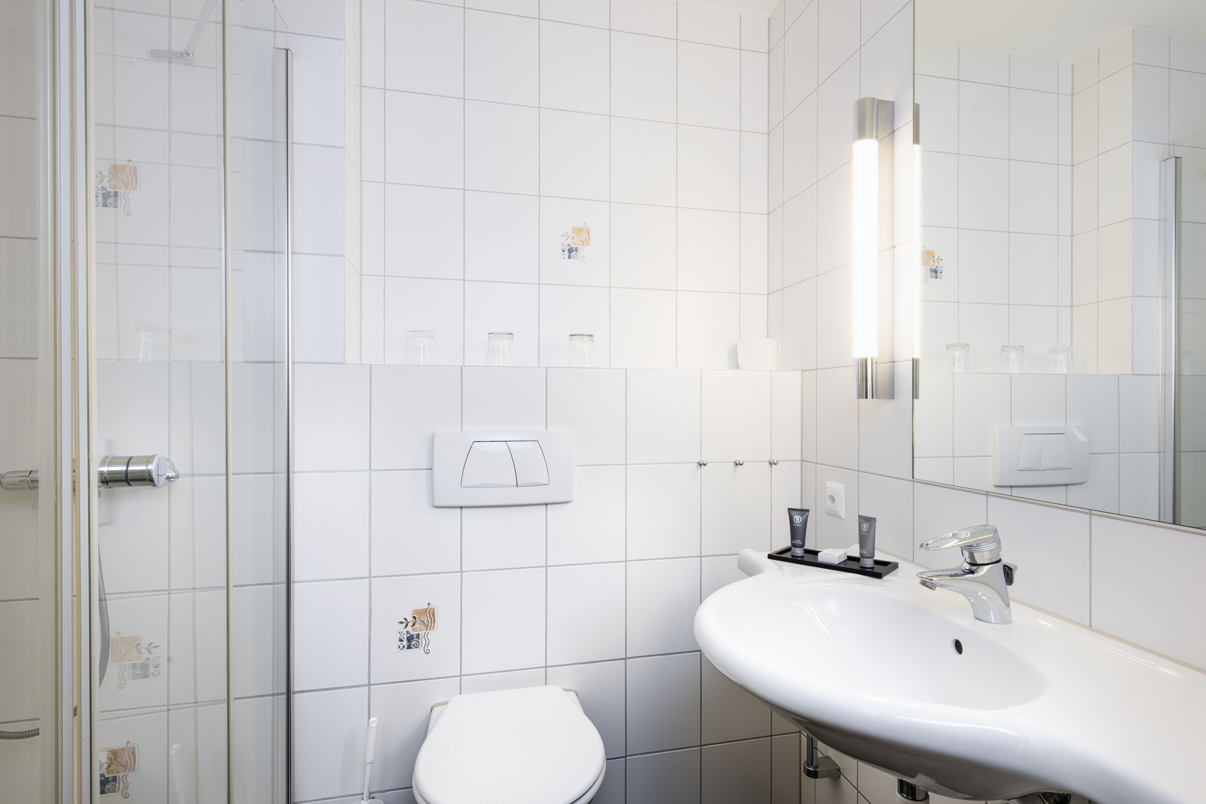 Un baño moderno con un lavamanos blanco, un inodoro y una ducha.