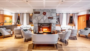 A modern lounge area with a stone fireplace, comfortable seating, and a wooden accent wall. - Hapimag Resort Flims (Flims)