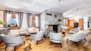 A modern lounge with a stone fireplace, comfortable seating, and a view of the outdoors. - Hapimag Resort Flims (Flims)