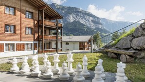 A wooden building with a balcony, a chessboard with oversized pieces, and a mountainous backdrop. - Hapimag Resort Flims (Flims)