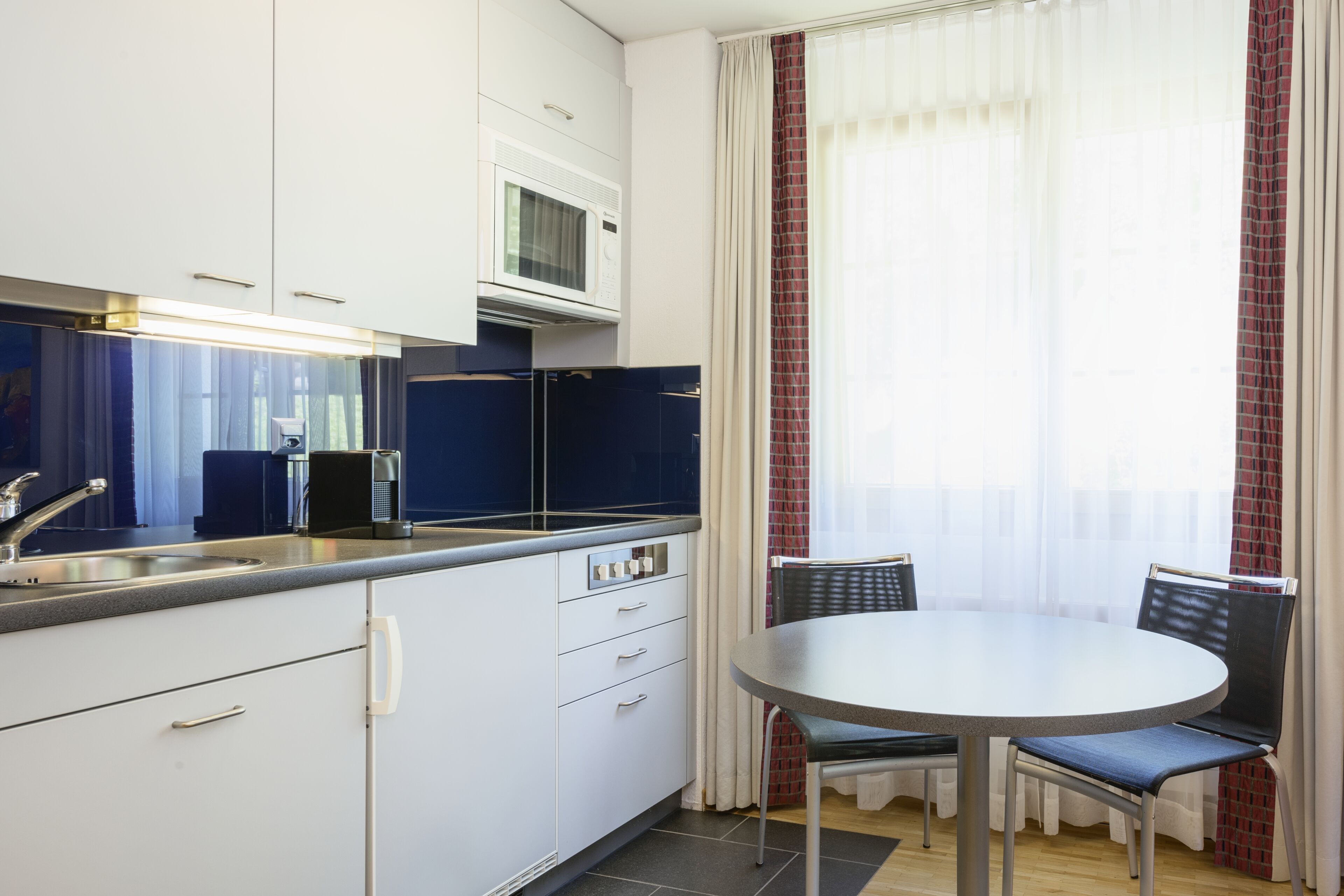 A compact kitchen with a microwave, sink, and a dining area with a table and chairs.