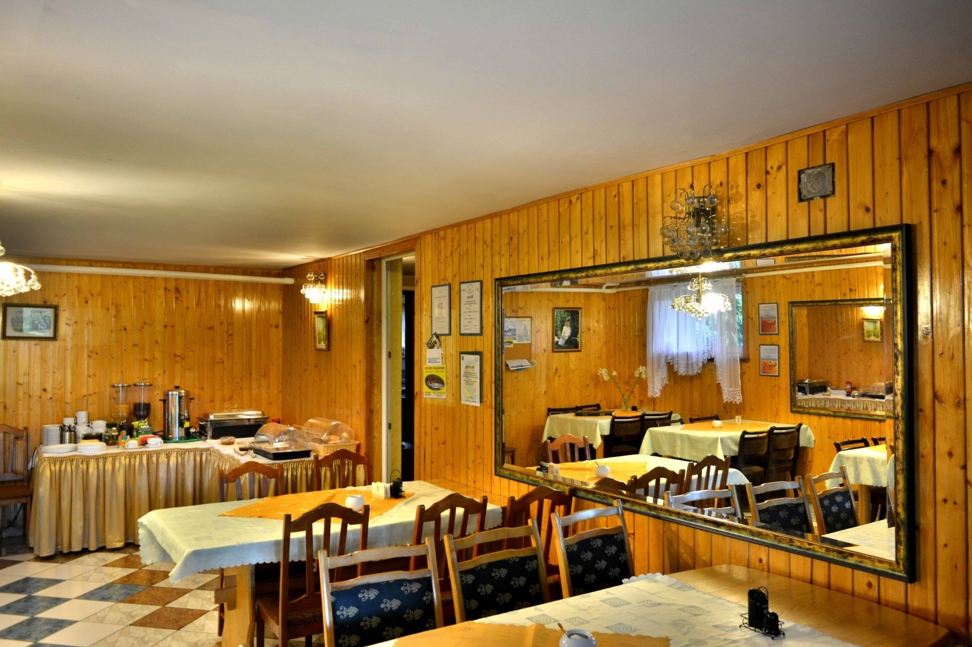 A dining area with wooden paneling, a large mirror, and a checkered floor.