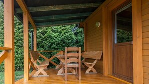 A wooden deck with a covered area, featuring a table and two wooden chairs. - Agroturystyka Katarzyna Tarasiewicz (Suwalki)