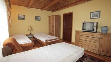 Quarto com duas camas, armários de madeira, televisão e quadros nas paredes.