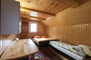 A small, wooden cabin room with a single bed, a sofa, a table, and a window. - Agroturystyka Katarzyna Tarasiewicz (Suwalki)