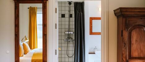 Un baño con ducha, espejo y mueble de madera.
