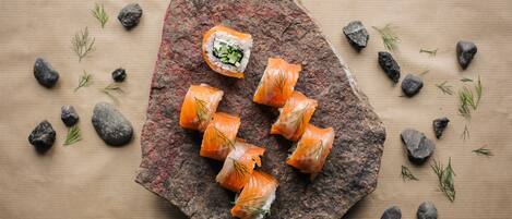Sushi pieces on a rock with scattered rocks and green leaves around.