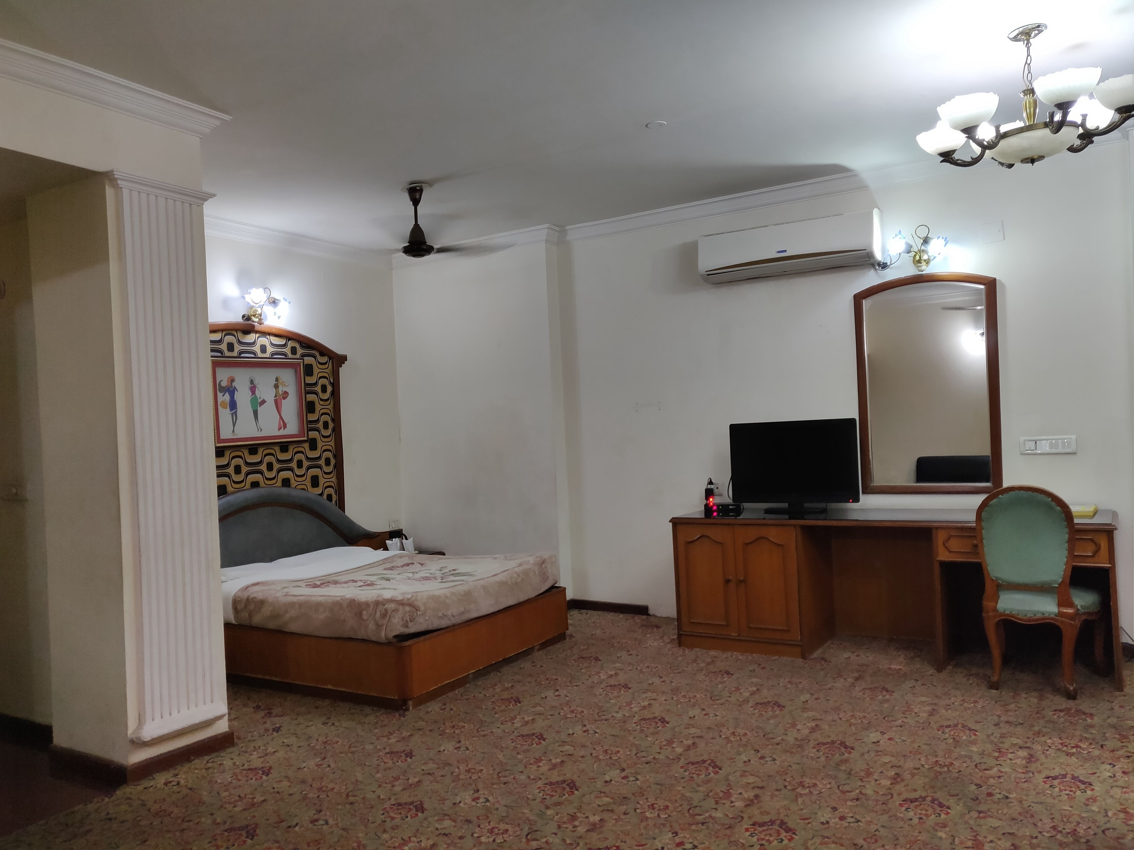 A bedroom with a bed, a dresser, a television, a chair, and a ceiling fan.