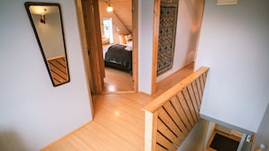 Una escalera de madera que lleva a un dormitorio con una cama, un espejo y un papel tapiz estampado.