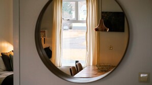 Un espejo circular que refleja un comedor con una mesa, sillas y una lámpara colgante.