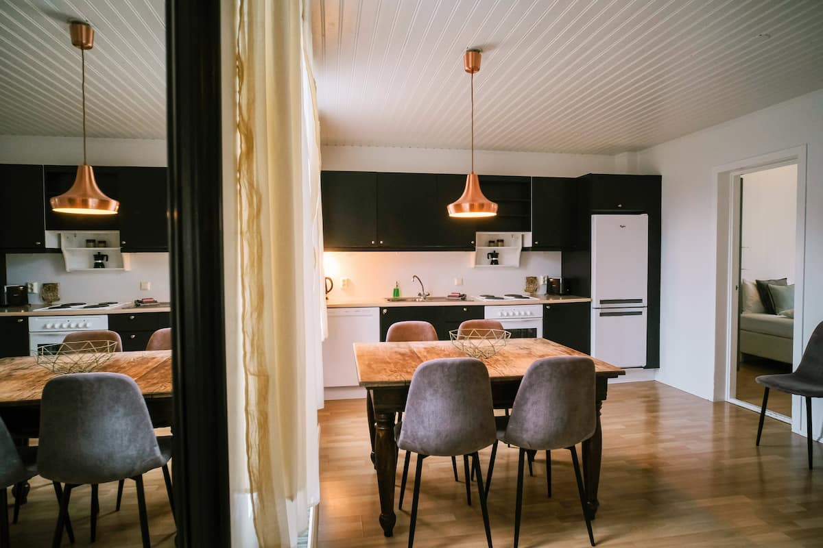 A modern kitchen with dark cabinets, a wooden dining table, and two pendant lights.