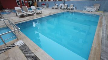 An indoor swimming pool with lounge chairs and a diving board.