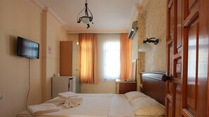 Een hotelkamer met een bed, televisie, bureau, spiegel en deur.