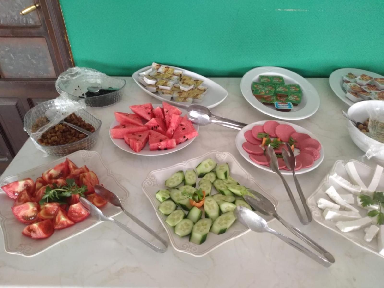 A buffet table with various food items including watermelon, cucumber slices, and other dishes.